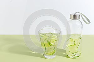 A bottle of cucumber water on a light green background. Minimalistic creative concept. Copy space