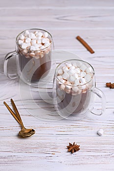 Glass cup of brown cocoa with marshmeloy, on white wooden background