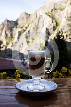 Glass cup with cappuccino on the background of Matka canyon, North Macedonia