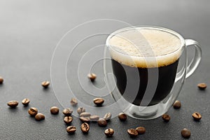 glass cup of espresso and coffee beans on grey table