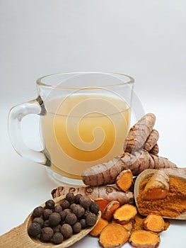 Glass cup with golden milk and wooden spoon with ingredients