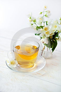 Glass cup of green tea with bouquet of jasmine