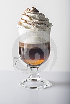 Glass cup with handle containing coffee.