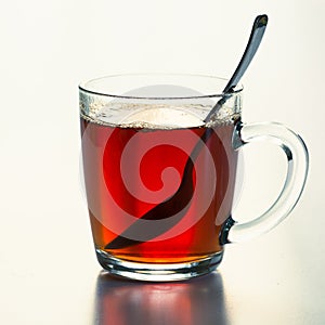 Glass cup of hot black tea on white. Close up.