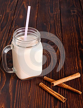 Glass cup of hot cocoa with milk, cinnamon and straw tube