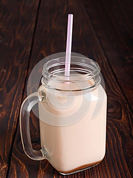 Glass cup of hot cocoa with milk and with straw tube