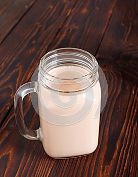 Glass cup of hot cocoa with milk on wooden table