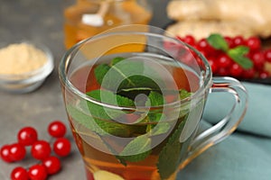 Glass cup of immunity boosting drink and ingredients on grey table, closeup