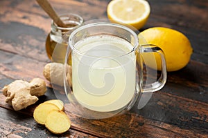 Glass cup of lemon and ginger tea and honey rustic wooden background