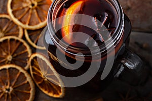 glass cup with mulled wine with dried oranges and spices on a wooden table