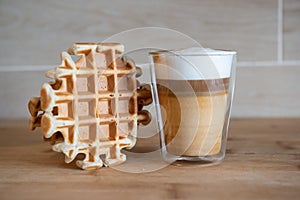Glass cup of multilayer coffee with mini stroopwafel, syrupwaffles cookies on light gray background with copy space