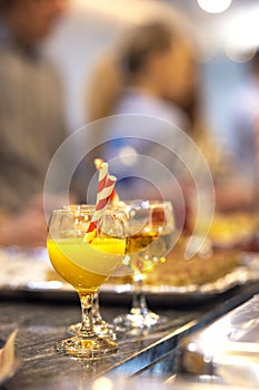 Glass cup with natural fresh orange juice at a children\'s party with a paper stream on a table, healthy citrus cocktail
