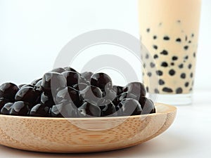 A glass cup of pearl milk tea also called bubble tea and a plate of tapioca ball on white background. photo
