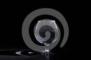 Glass cup with pure mineral water with bubbles on a black background