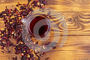 Glass cup of red hibiscus tea carcade, roselle on wooden table