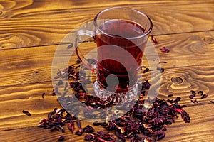 Glass cup of red hibiscus tea carcade, roselle on wooden table