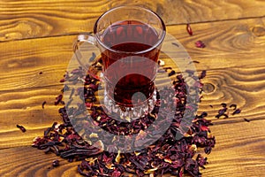 Glass cup of red hibiscus tea carcade, roselle on wooden table