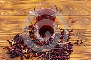 Glass cup of red hibiscus tea carcade, roselle on wooden table