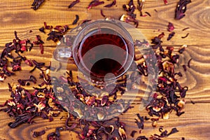 Glass cup of red hibiscus tea carcade, roselle on wooden table