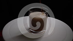In a glass Cup standing on a white round platform poured Cola in slow motion