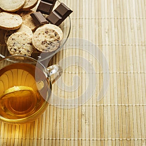 Glass cup of tea with biscuits and lemon on a light wooden background.Cup of tea with lemon and biscuits