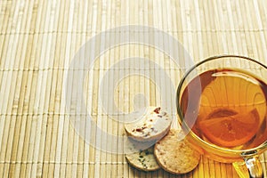 Glass cup of tea with biscuits and lemon on a light wooden background.Cup of tea with lemon and biscuits