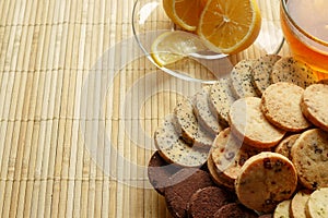 Glass cup of tea with biscuits and lemon on a light wooden background.Cup of tea with lemon and biscuits