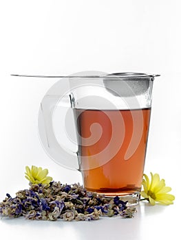 Glass cup with tea inside and a strainer for infusions