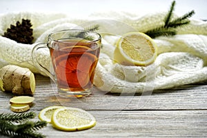 Glass cup of tea with lemon and ginger root slices, mint leaf on glass saucer on a rustic wooden table on background of