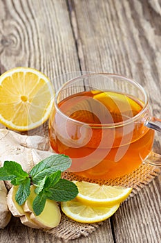 A glass cup of tea with lemon, mint and ginger