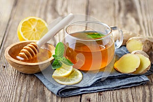 A glass cup of tea with lemon, mint, ginger and honey