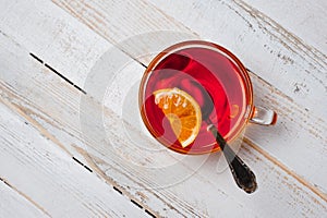 Glass cup with tea and lemon standing on a white painted wooden surface. Background for hot drinks. Soft and tonic drinks