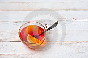 Glass cup with tea and lemon standing on a white painted wooden surface. Background for hot drinks. Soft and tonic drinks