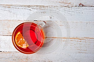 Glass cup with tea and lemon standing on a white painted wooden surface. Background for hot drinks. Soft and tonic drinks