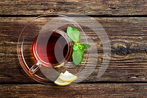 Glass cup with tea, mint and lemon on wooden rustic background. Top view.