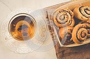 glass cup of tea and rolls with poppy in a wooden basket/glass cup of tea and rolls with poppy in a wooden basket on a white table