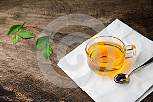Glass cup of tea and spoons with green leaves tea on old wooden