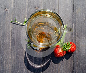 Glass cup with tea and strawberries on the table