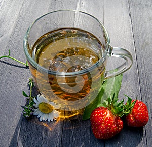 Glass cup with tea and strawberries on the table