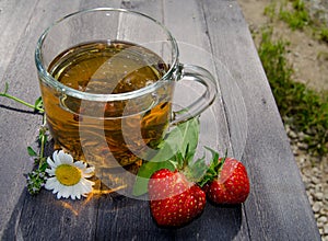 Glass cup with tea and strawberries on the table