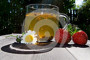 Glass cup with tea and strawberries on the table