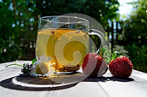 Glass cup with tea and strawberries on the table