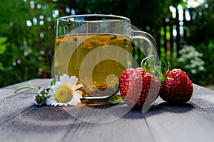 Glass cup with tea and strawberries on the table