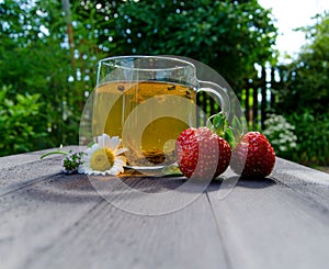 Glass cup with tea and strawberries on the table