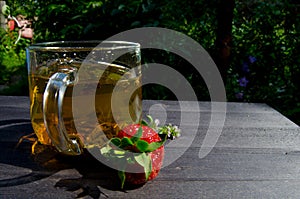 Glass cup with tea and strawberries on the table