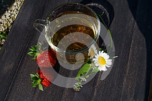 Glass cup with tea and strawberries on the table