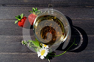 Glass cup with tea and strawberries on the table