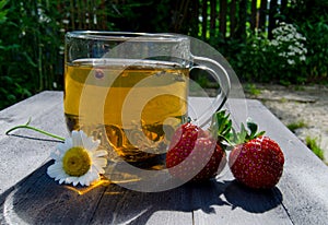 Glass cup with tea and strawberries on the table