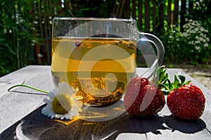 Glass cup with tea and strawberries on the table