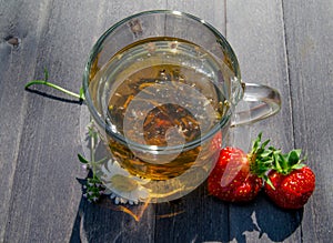 Glass cup with tea and strawberries on the table